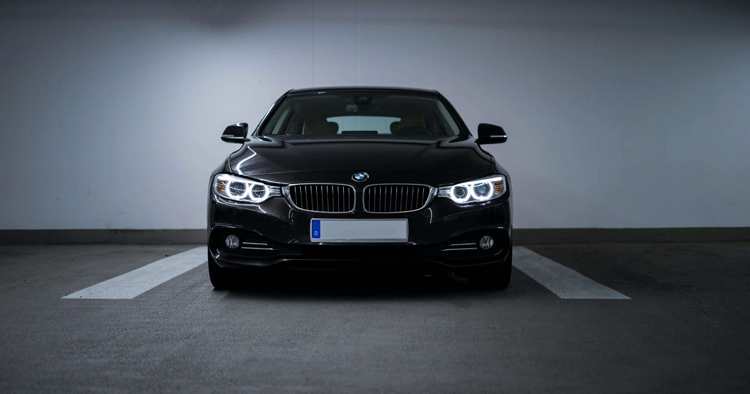 Front view of a luxurious black BMW parked in a dimly lit garage.
