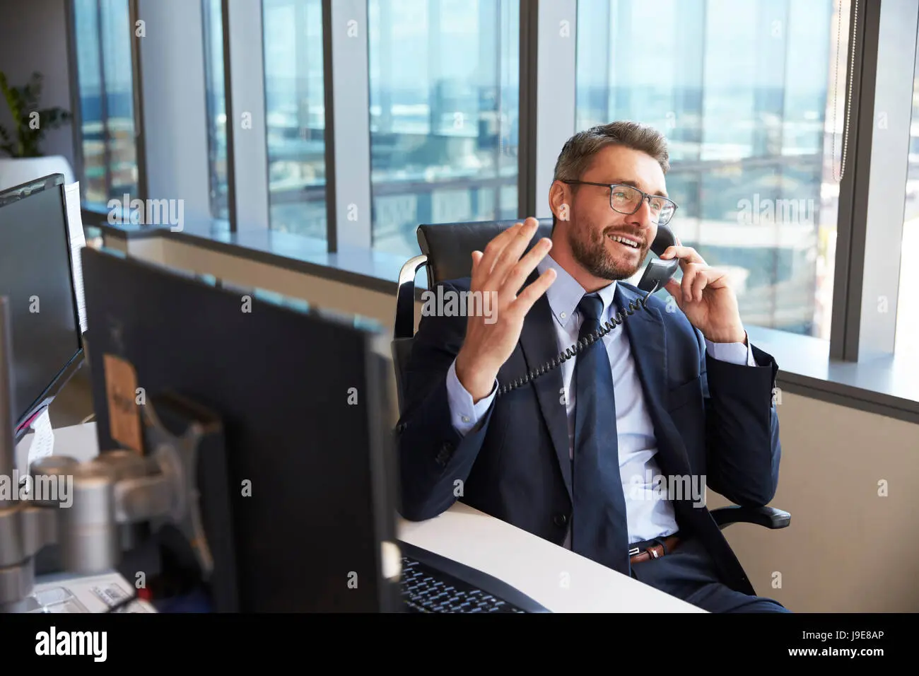 businessman making phone call sitting at desk in office j9e8ap